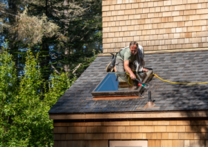 man on the roof cleaning a window using a brush with flowing water
