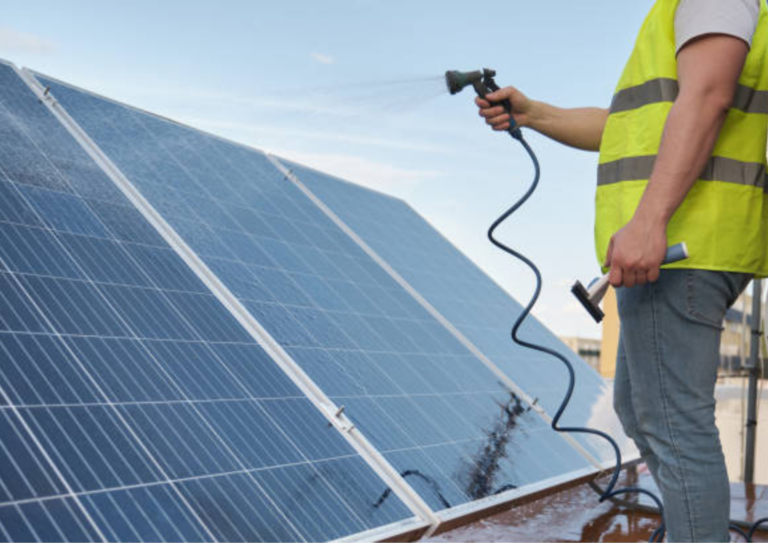 a man spraying solar panel with water